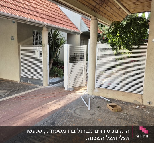 שערי מתכת לבנים בכניסה לבית עם גג רעפים אדום